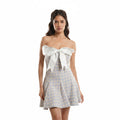 Woman wearing a strapless dress with a large bow on a white background